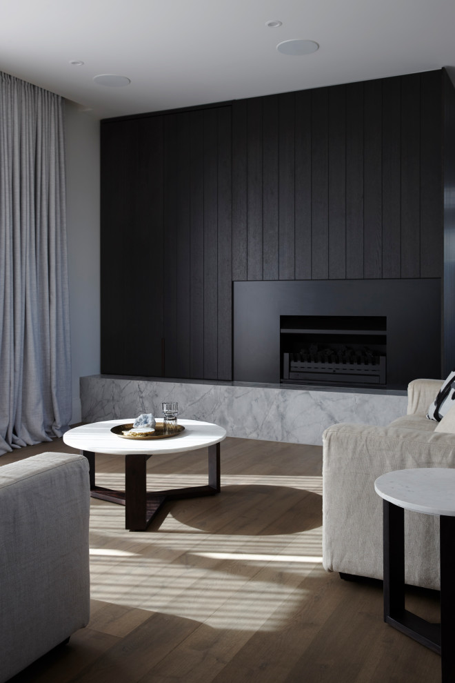 Mid-sized modern formal open concept living room in Auckland with black walls, medium hardwood floors, a standard fireplace, a metal fireplace surround, a concealed tv, brown floor and planked wall panelling.