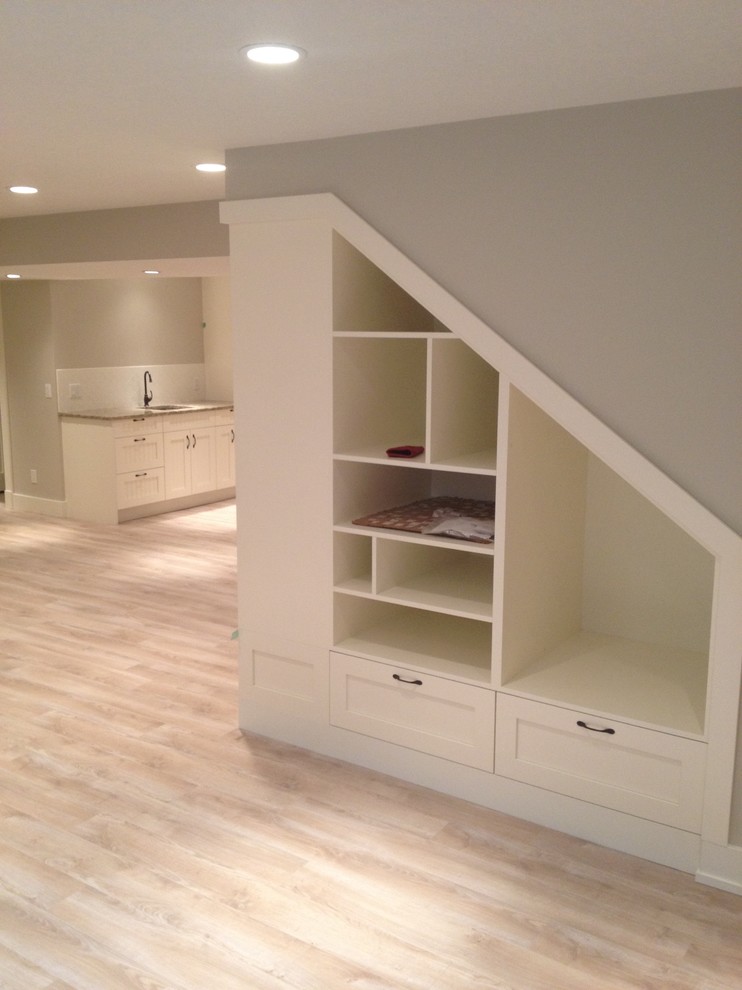Mid-sized transitional fully buried basement in Calgary with beige walls, light hardwood floors and beige floor.