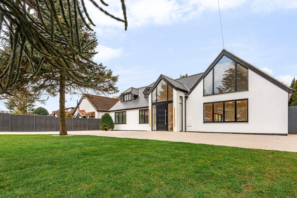 Großes, Zweistöckiges Modernes Einfamilienhaus mit Putzfassade, beiger Fassadenfarbe, Satteldach, Ziegeldach, grauem Dach und Wandpaneelen in Surrey