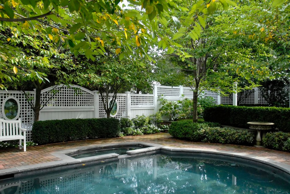 Photo of a large traditional backyard rectangular lap pool in Other with a hot tub and brick pavers.
