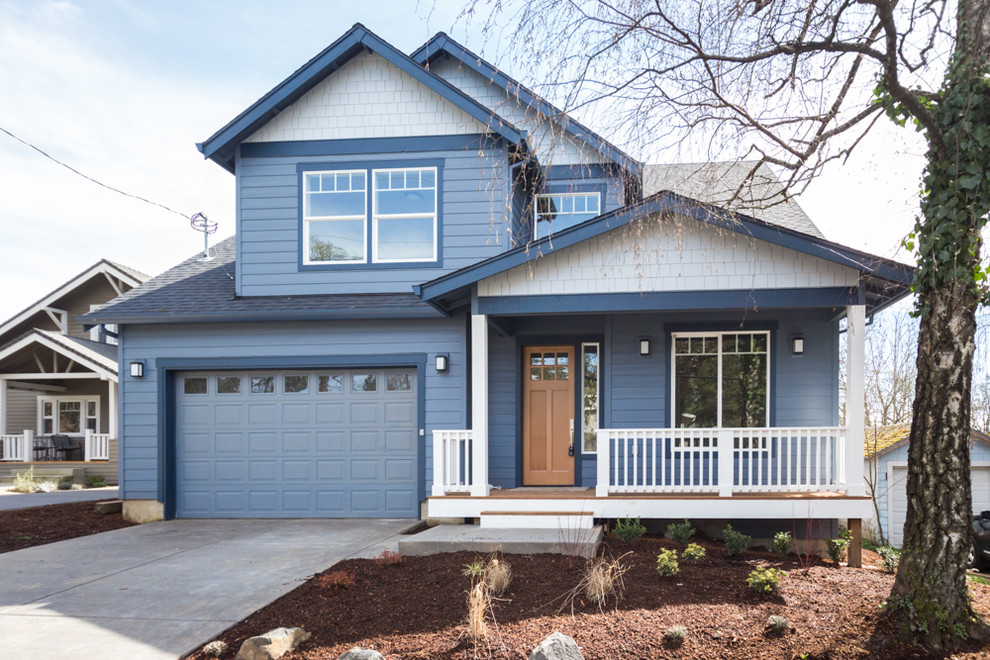 This is an example of a mid-sized traditional two-storey blue house exterior in Portland with vinyl siding, a gable roof and a shingle roof.