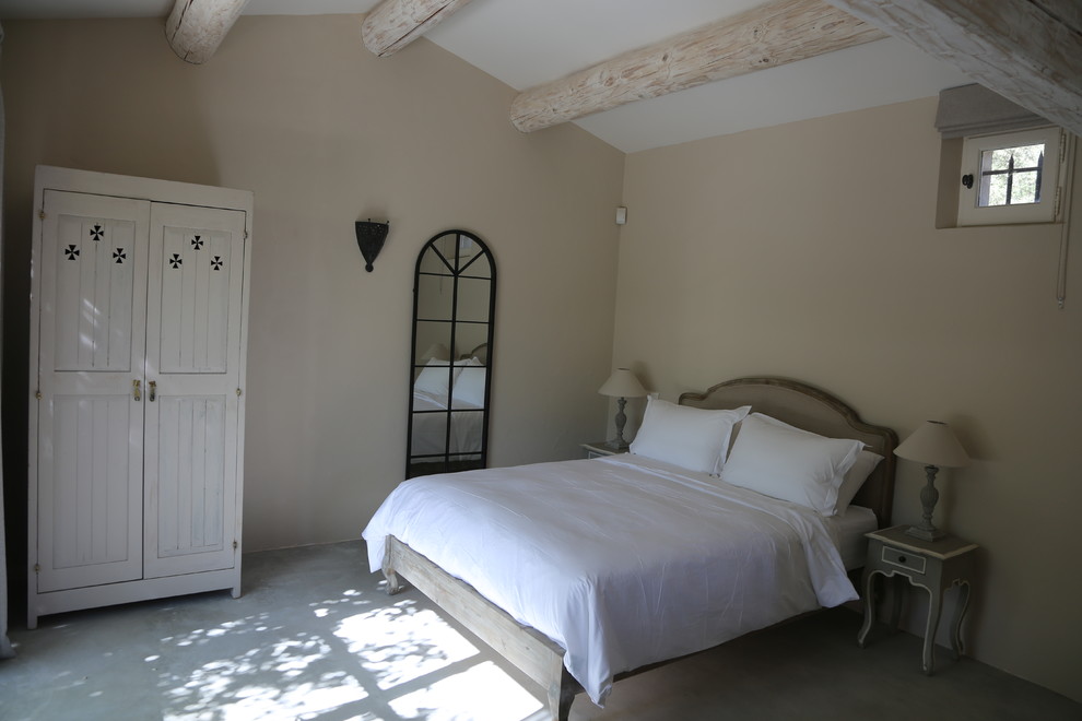 Photo of a large country guest bedroom in Surrey with beige walls and concrete floors.