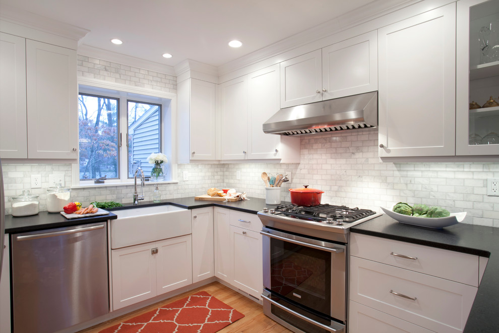 This is an example of a transitional u-shaped separate kitchen in Bridgeport with a farmhouse sink, flat-panel cabinets, white cabinets, granite benchtops, white splashback, stone tile splashback and stainless steel appliances.
