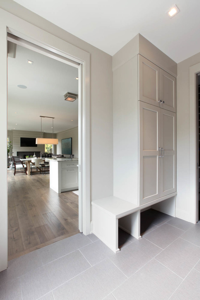 This is an example of a small transitional entryway in Grand Rapids with grey walls, porcelain floors, a single front door and a dark wood front door.
