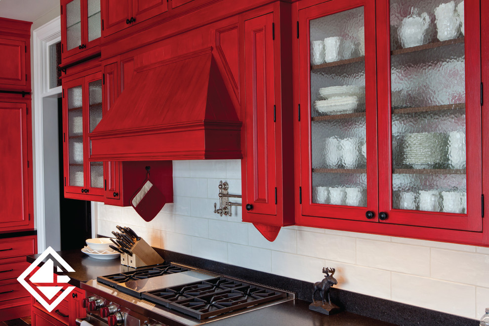 Huge mountain style l-shaped medium tone wood floor eat-in kitchen photo with a farmhouse sink, raised-panel cabinets, red cabinets, granite countertops, white backsplash, stainless steel appliances and an island