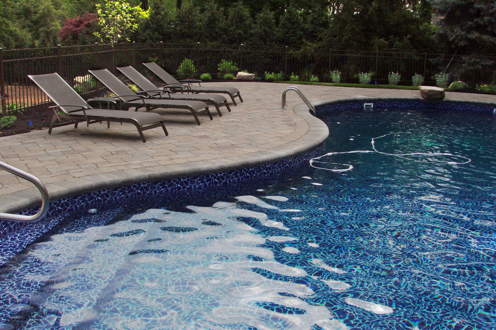 Design ideas for a contemporary backyard custom-shaped pool in New York with concrete pavers.