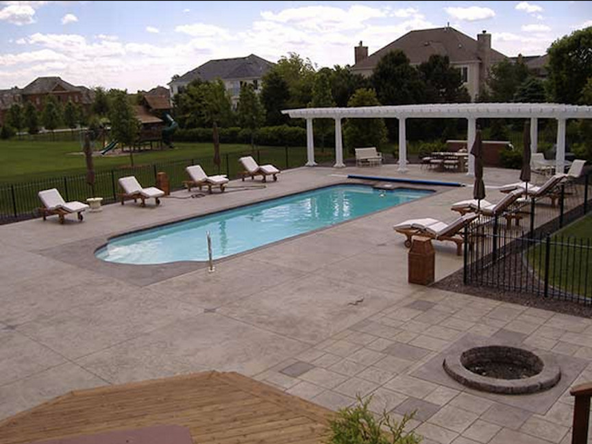 Large midcentury backyard rectangular lap pool in Chicago with a pool house and concrete pavers.