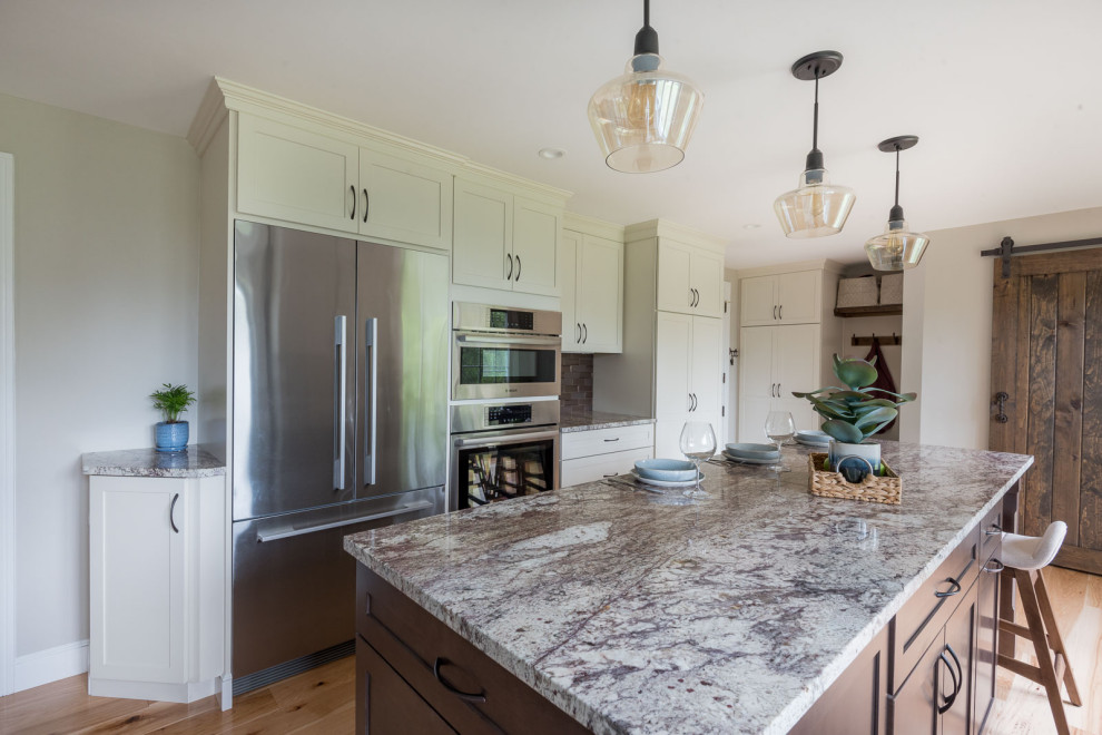Inspiration for a mid-sized transitional u-shaped light wood floor and brown floor eat-in kitchen remodel in Boston with an undermount sink, shaker cabinets, white cabinets, granite countertops, brown backsplash, glass tile backsplash, stainless steel appliances, an island and multicolored countertops
