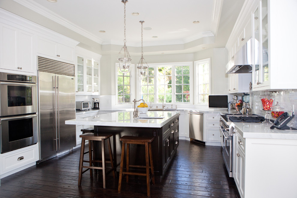 This is an example of a traditional kitchen in Los Angeles with glass-front cabinets and stainless steel appliances.