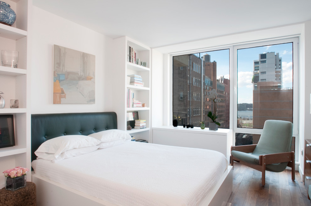Contemporary bedroom in New York with white walls and medium hardwood floors.