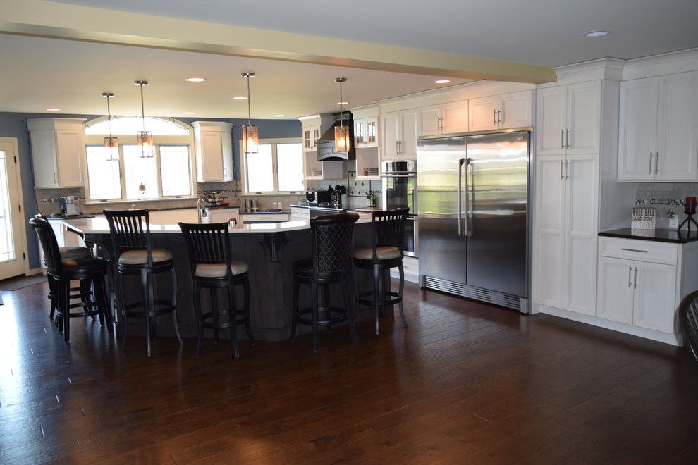 Home design - transitional medium tone wood floor home design idea with an undermount sink, louvered cabinets, white cabinets, quartz countertops, gray backsplash, ceramic backsplash and stainless steel appliances