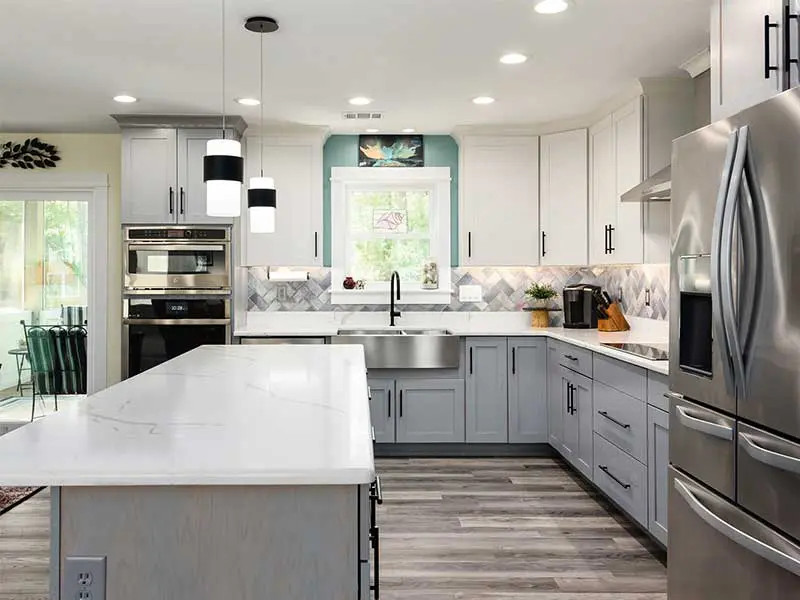 Foto de cocina costera con puertas de armario grises, electrodomésticos de acero inoxidable y una isla