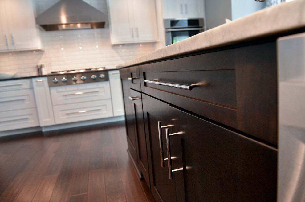 Transitional dark wood floor home design photo in Cleveland with a drop-in sink, recessed-panel cabinets, white backsplash, ceramic backsplash, stainless steel appliances and an island