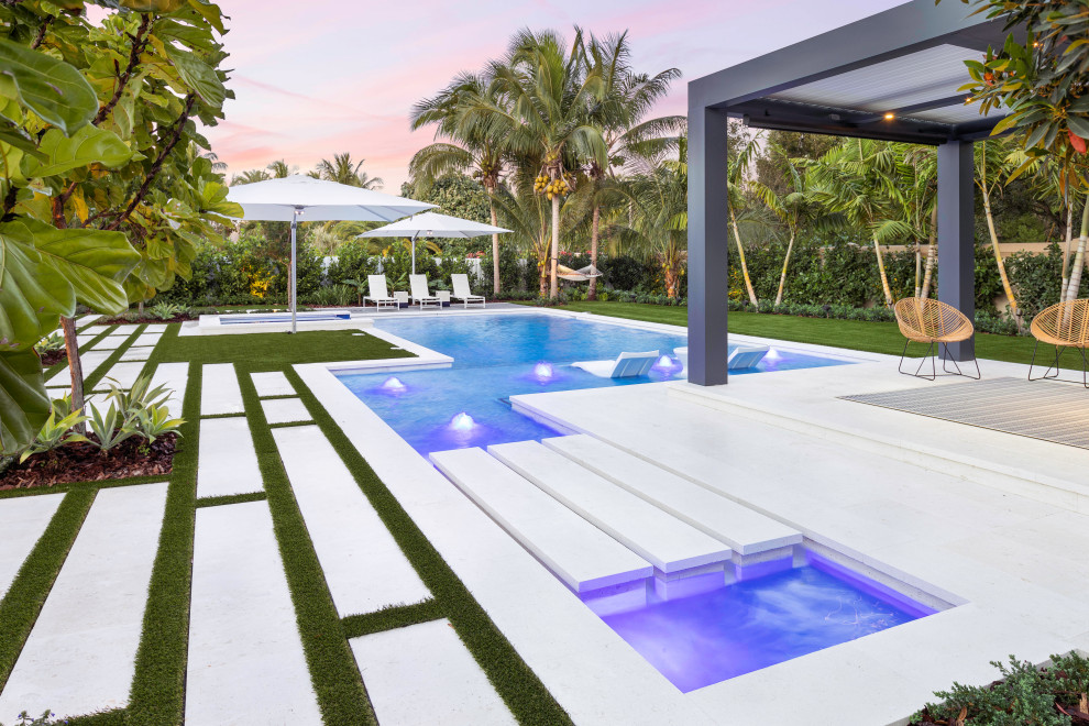 Photo of a large modern backyard custom-shaped lap pool in Miami with a hot tub.