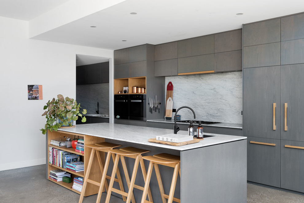 Mid-sized contemporary galley kitchen in Melbourne with flat-panel cabinets, marble benchtops, marble splashback, black appliances, concrete floors, with island, grey floor, an undermount sink, grey cabinets, white splashback and white benchtop.