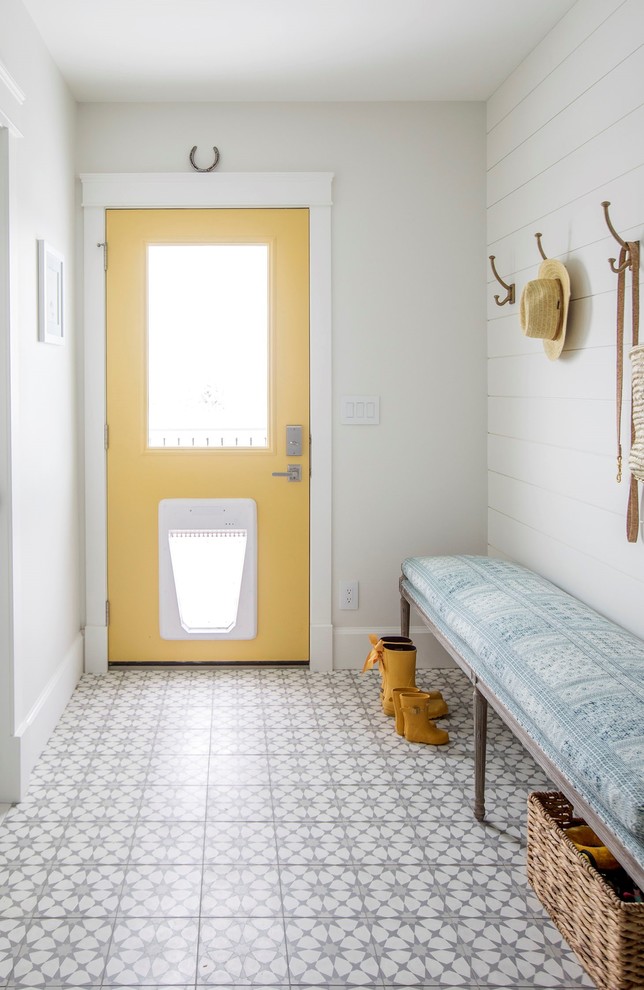 This is an example of a country entryway in Vancouver with a yellow front door, white walls, a single front door and multi-coloured floor.