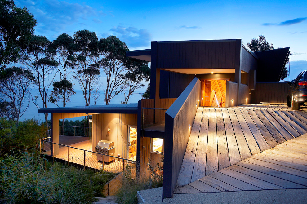 Inspiration for a mid-sized beach style two-storey grey exterior in Melbourne with wood siding and a flat roof.