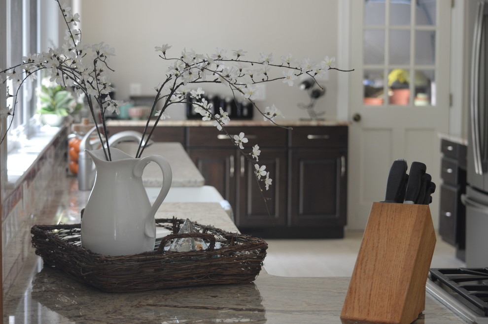 Large transitional l-shaped porcelain tile and beige floor eat-in kitchen photo with a farmhouse sink, raised-panel cabinets, brown cabinets, granite countertops, white backsplash, ceramic backsplash, stainless steel appliances and a peninsula