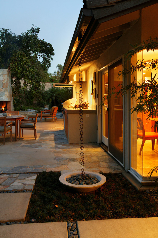 Large midcentury backyard patio in Orange County with natural stone pavers, a fire feature and no cover.