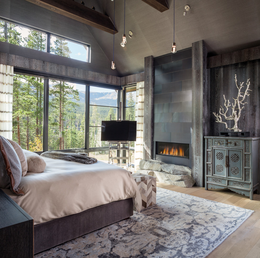 Country master bedroom in Denver with light hardwood floors, a ribbon fireplace, beige floor, grey walls, a metal fireplace surround, vaulted and wallpaper.