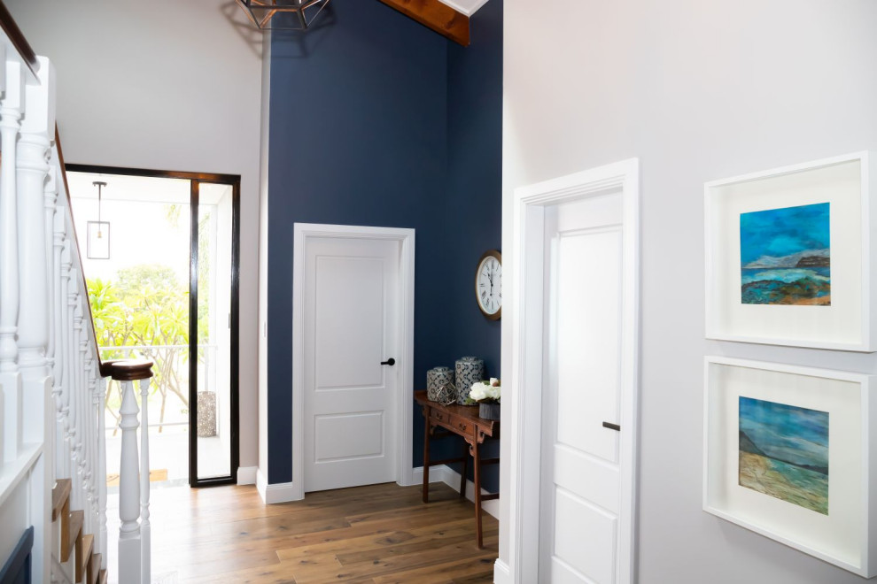 シドニーにある中くらいなトランジショナルスタイルのおしゃれな玄関ロビー (青い壁、ラミネートの床、淡色木目調のドア、茶色い床) の写真
