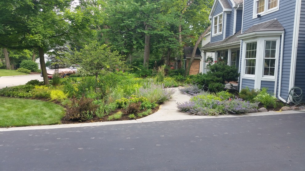 This is an example of a mid-sized transitional front yard partial sun driveway for summer in Chicago with a garden path and concrete pavers.