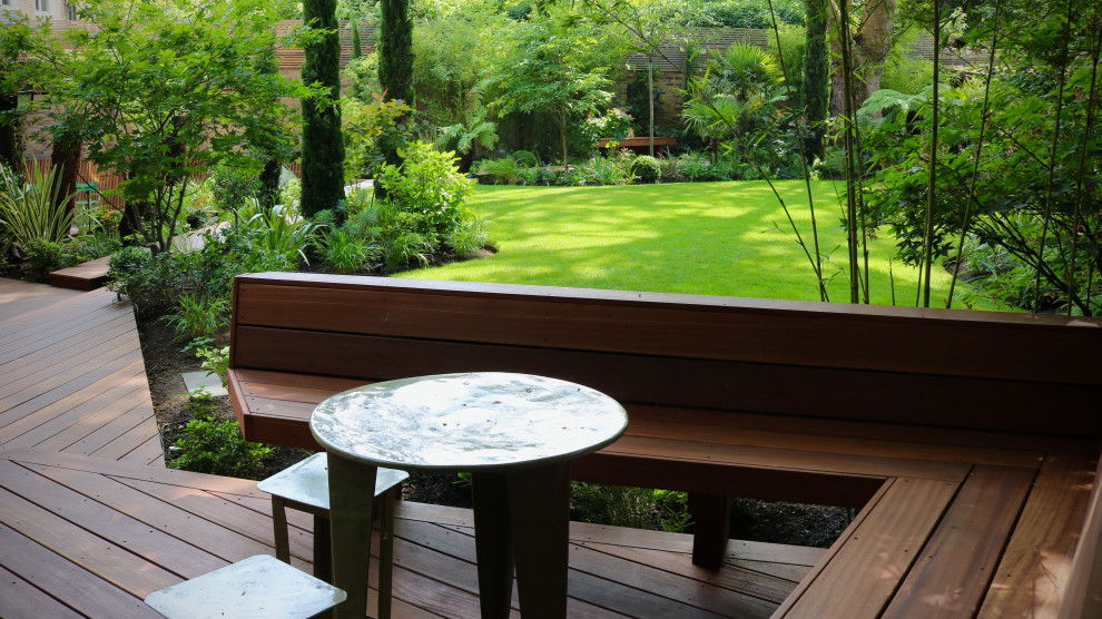 Exemple d'un jardin arrière exotique avec une exposition partiellement ombragée et une terrasse en bois.