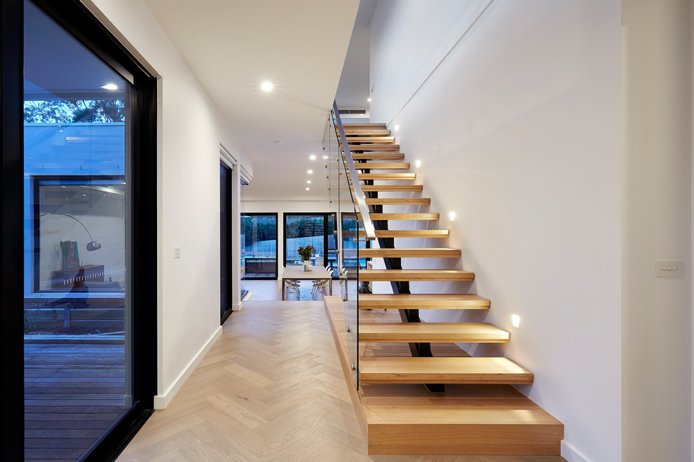 This is an example of a contemporary wood floating staircase in Melbourne with open risers and glass railing.