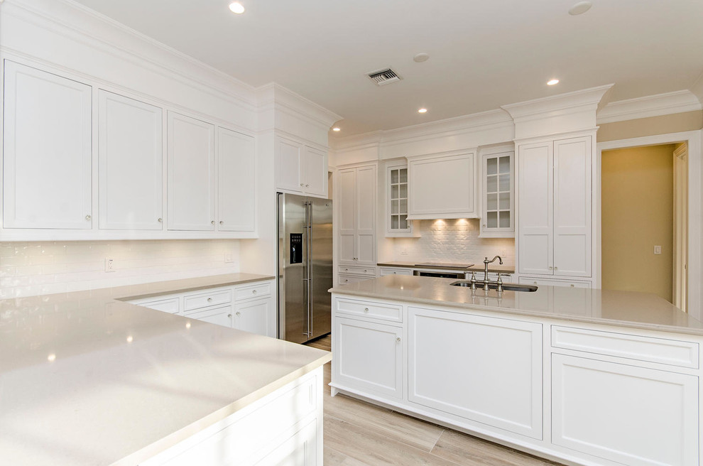 Example of a transitional eat-in kitchen design in Miami with shaker cabinets, white cabinets and an island