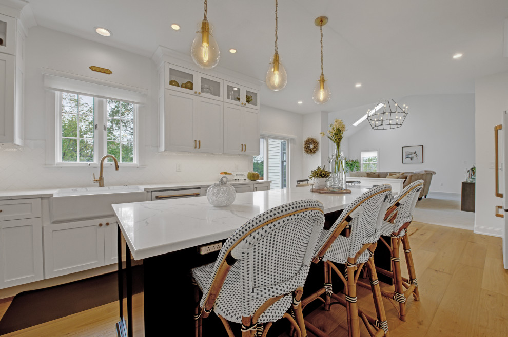 Inspiration for a mid-sized transitional l-shaped eat-in kitchen in Philadelphia with a farmhouse sink, shaker cabinets, brown cabinets, quartz benchtops, white splashback, porcelain splashback, white appliances, light hardwood floors, with island, brown floor and yellow benchtop.