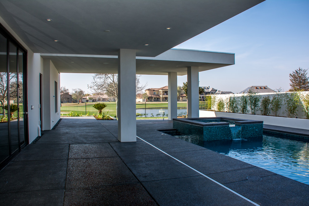 Photo of a large contemporary backyard patio in Los Angeles with a water feature, concrete slab and a roof extension.