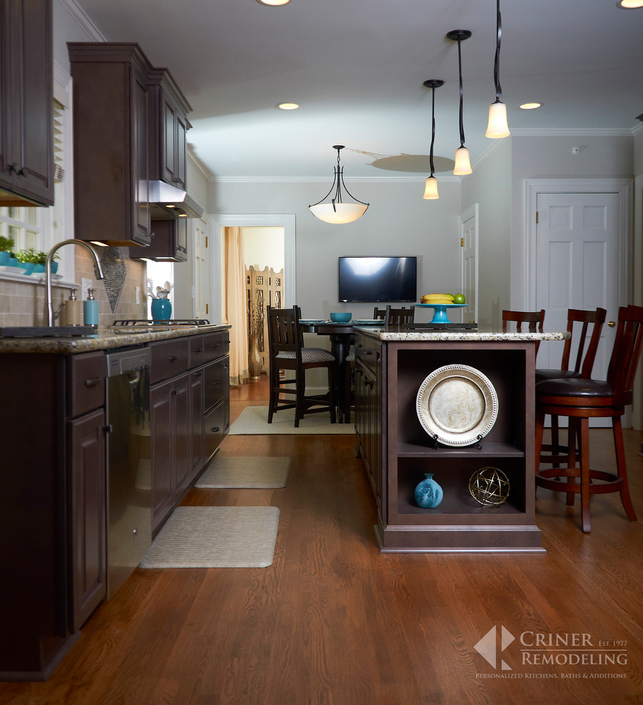 Example of a transitional light wood floor eat-in kitchen design with shaker cabinets, dark wood cabinets, granite countertops, beige backsplash, glass tile backsplash, stainless steel appliances and an island