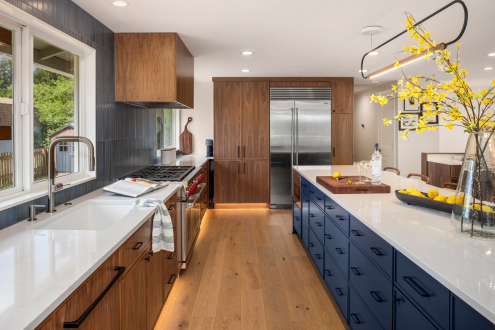 Large trendy light wood floor and brown floor open concept kitchen photo in Seattle with an undermount sink, flat-panel cabinets, medium tone wood cabinets, quartz countertops, blue backsplash, ceramic backsplash, stainless steel appliances, an island and white countertops