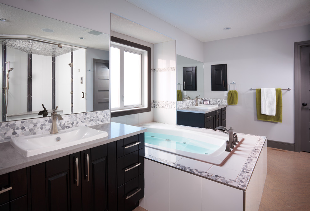 This is an example of a large contemporary master bathroom in Calgary with a drop-in tub, white walls, flat-panel cabinets, black cabinets, an alcove shower, black and white tile, gray tile, pebble tile, porcelain floors, an undermount sink and granite benchtops.