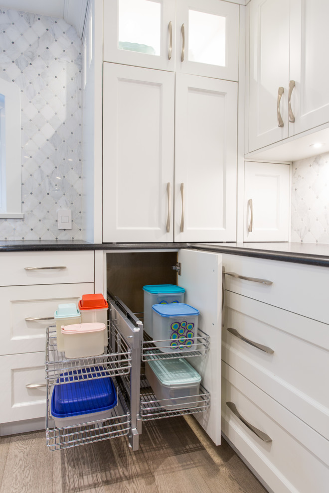 Inspiration for a large transitional l-shaped medium tone wood floor and beige floor eat-in kitchen remodel in Vancouver with an undermount sink, shaker cabinets, white cabinets, granite countertops, gray backsplash, marble backsplash, stainless steel appliances, an island and black countertops