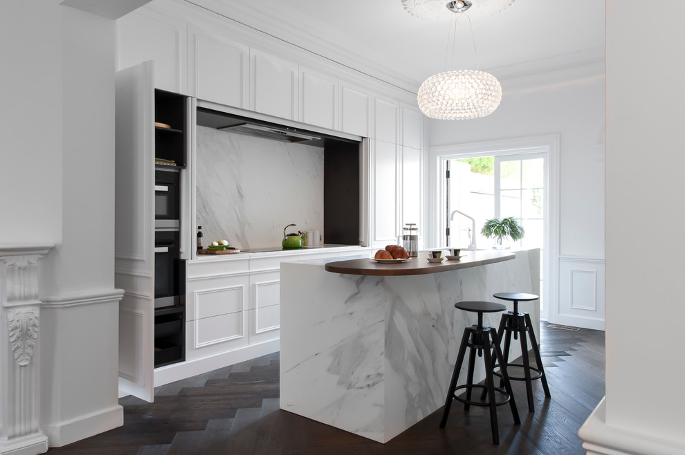 Mid-sized traditional galley eat-in kitchen in Sydney with an undermount sink, white cabinets, marble benchtops, white splashback, stone slab splashback, white appliances, dark hardwood floors and with island.