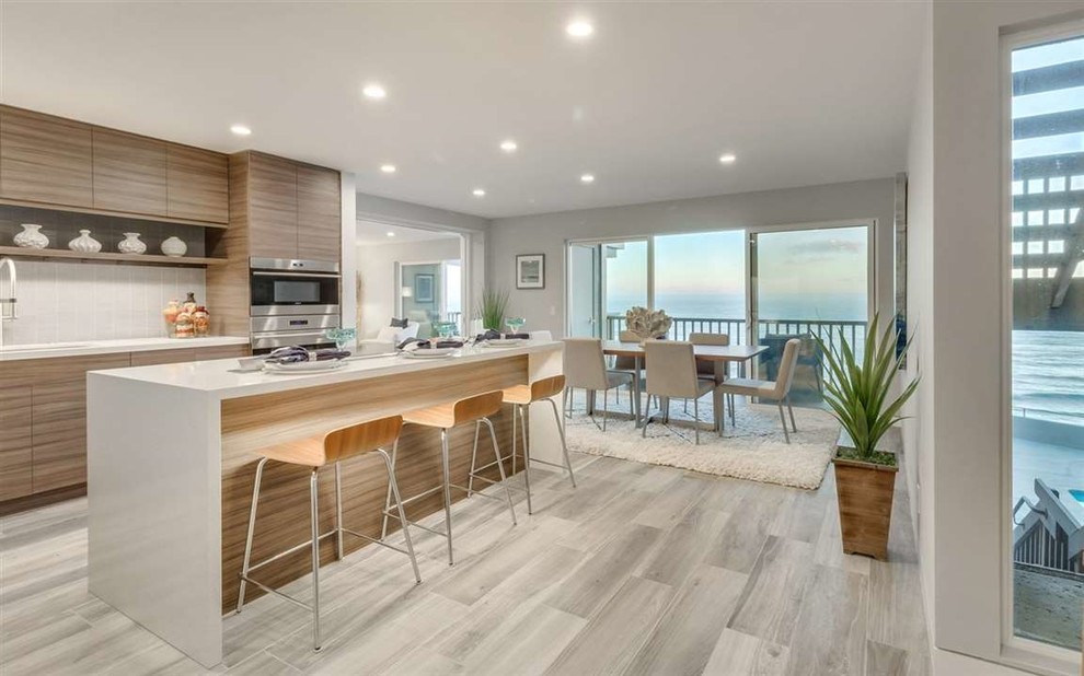Photo of a mid-sized modern galley eat-in kitchen in San Diego with light wood cabinets, quartzite benchtops, beige splashback, with island and white benchtop.