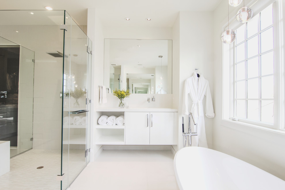 Large modern master bathroom in DC Metro with flat-panel cabinets, white cabinets, a freestanding tub, white tile, white walls, an undermount sink, solid surface benchtops, a curbless shower, a two-piece toilet, stone tile, cement tiles, white floor and a hinged shower door.