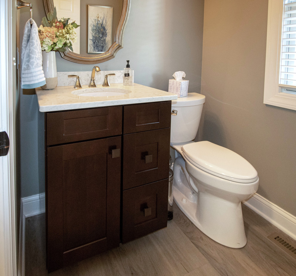 Inspiration for a small transitional powder room in Cleveland with flat-panel cabinets, brown cabinets, a two-piece toilet, beige walls, vinyl floors, an undermount sink, engineered quartz benchtops, beige floor, beige benchtops and a built-in vanity.