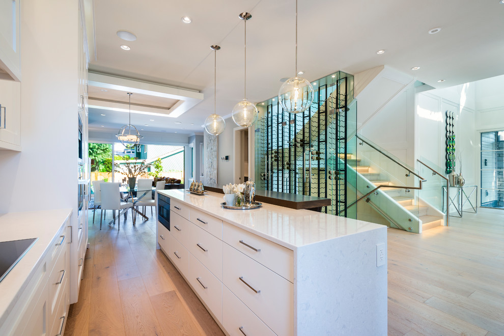 Example of a mid-sized transitional l-shaped light wood floor and beige floor open concept kitchen design in Vancouver with an undermount sink, shaker cabinets, white cabinets, quartz countertops, gray backsplash, mosaic tile backsplash, paneled appliances, an island and gray countertops