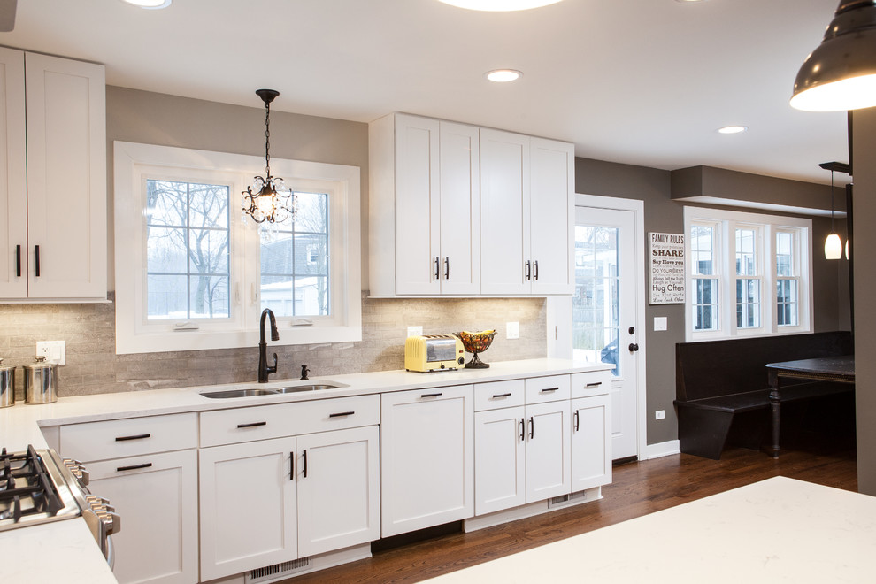 This is an example of a mid-sized contemporary u-shaped eat-in kitchen in Chicago with shaker cabinets, white cabinets, quartz benchtops, stainless steel appliances, medium hardwood floors and a peninsula.