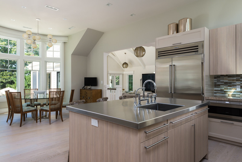 Inspiration for a mid-sized traditional kitchen in Boston with an undermount sink, flat-panel cabinets, light wood cabinets, multi-coloured splashback, glass tile splashback, stainless steel appliances, light hardwood floors and with island.
