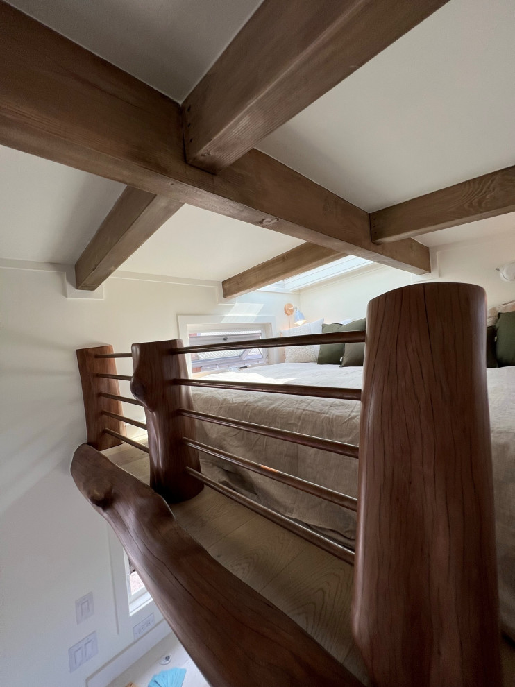 Foto de dormitorio tipo loft pequeño con paredes blancas, suelo de madera en tonos medios, suelo beige y vigas vistas