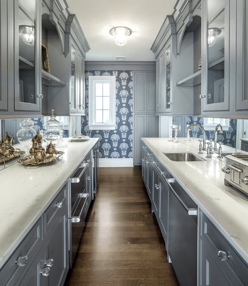 This is an example of a mid-sized transitional galley separate kitchen in New York with an undermount sink, recessed-panel cabinets, blue cabinets, marble benchtops, mirror splashback, stainless steel appliances, dark hardwood floors and no island.