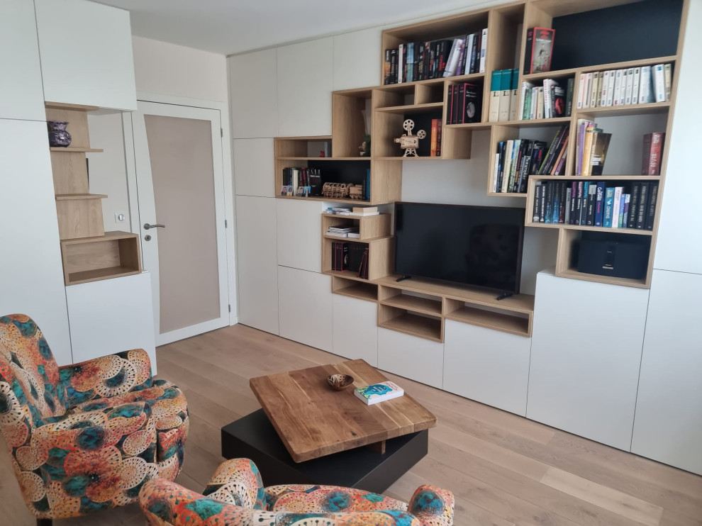 Стильный дизайн: маленькая открытая гостиная комната в скандинавском стиле с с книжными шкафами и полками, бежевыми стенами, светлым паркетным полом и отдельно стоящим телевизором для на участке и в саду - последний тренд