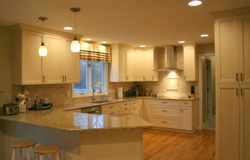 Large transitional u-shaped eat-in kitchen in Boston with an undermount sink, recessed-panel cabinets, beige cabinets, granite benchtops, beige splashback, stone tile splashback, stainless steel appliances, medium hardwood floors and a peninsula.