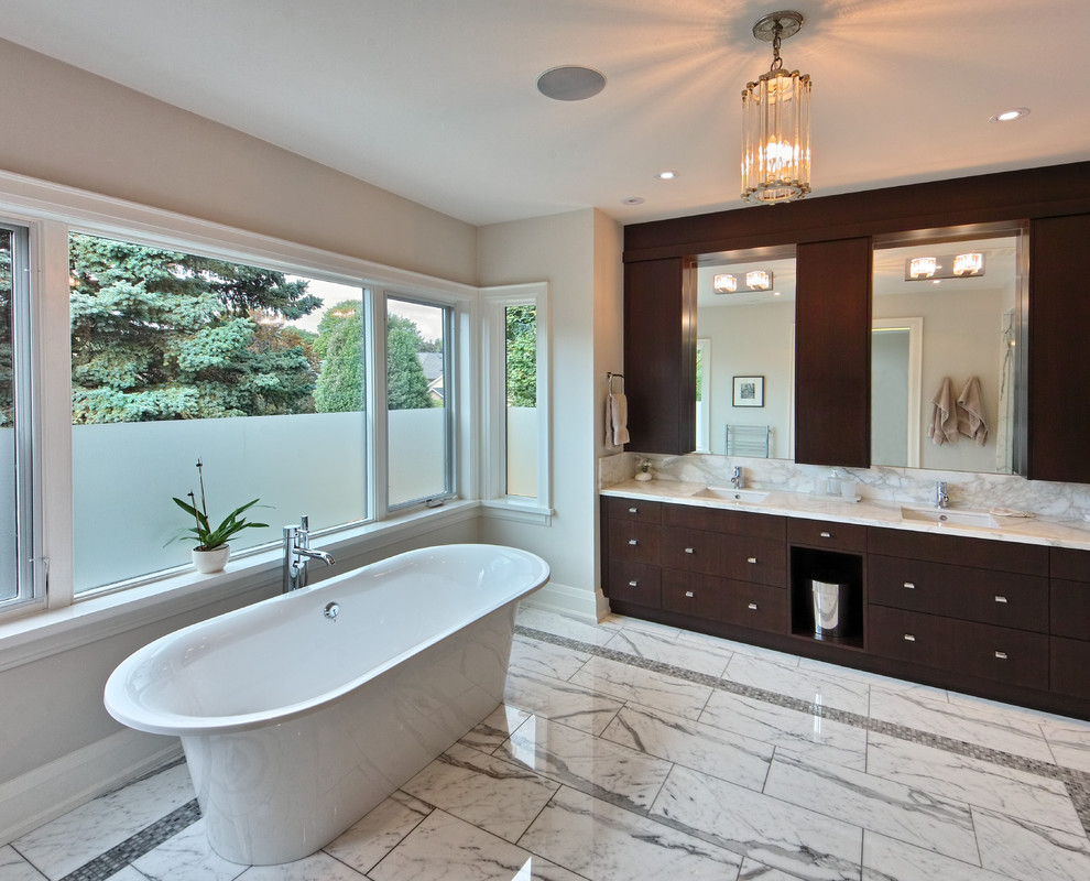 Mid-sized contemporary master bathroom in Toronto with an integrated sink, shaker cabinets, dark wood cabinets, marble benchtops, a freestanding tub, a double shower, a one-piece toilet, gray tile, stone tile, white walls, marble floors and grey floor.