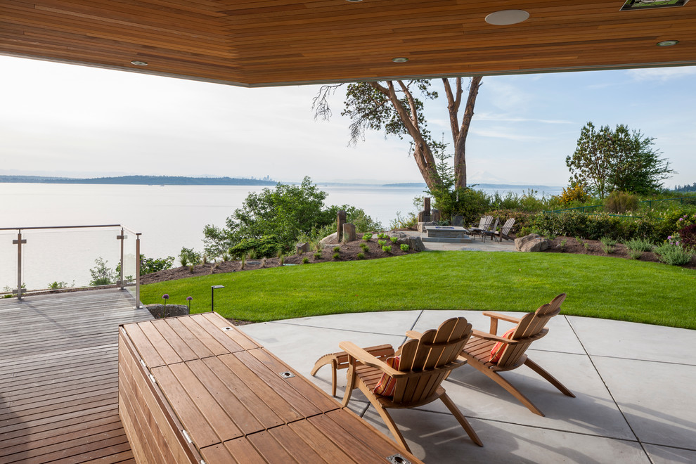 Mid-sized contemporary backyard deck in Seattle with a roof extension and a fire feature.