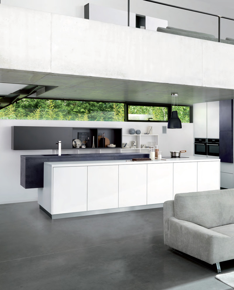 Modern u-shaped open plan kitchen in London with flat-panel cabinets, white cabinets, black appliances, with island, grey floor and white benchtop.