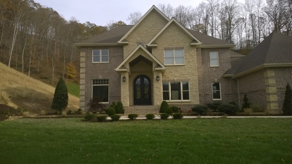 Large traditional two-storey beige exterior in Huntington with stone veneer and a hip roof.